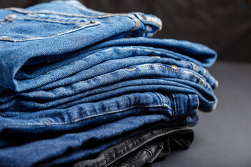 Blue jeans trousers stack textile texture fabric background. Stack of variety blue color jeans, denim jean textiles on black background.