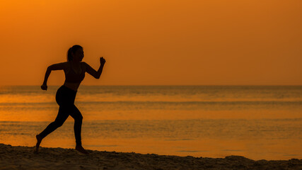 Silhouette athletic woman jogging exercise and relax and freedom on sand beach. People running and workout in sunset background. Lifestyle and Healthy Concept.