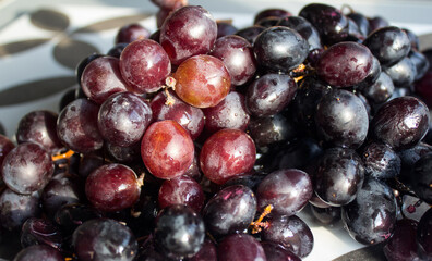Black grapes on a table. Top view photo of fresh summer fruits. Beautiful grapes close up photo. Water drops on grape. Eating fresh concept. 