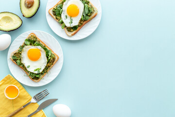 Breakfast with avocado toasts and fried eggs, top view
