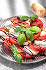 Salad caprese with mozzarella, sliced tomatoes, spices and fresh basil. Home made food. Concept for a tasty and healthy meal.