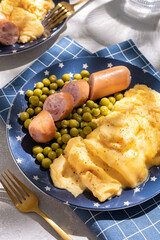 Breakfast with scrambled egg, sausages and green peas on white plate