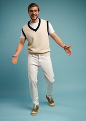 Full length of cheerful charming cute handsome man posing in front of camera isolated over blue color background