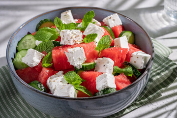 Summer salad with watermelon, mint, cucumber and feta cheese close up. Shadows