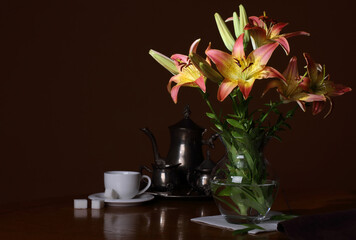 Naklejka na ściany i meble A vase with flowers lilies and a coffee set on a dark background