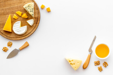 Set of cheese on wooden board with cheese knives, top view