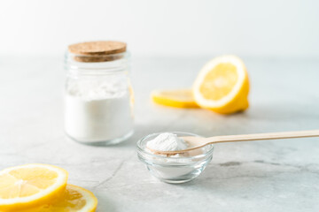 Eco friendly natural cleaners, jar with baking soda, lemon and wooden spoon on marble table...