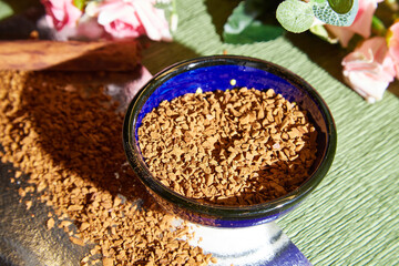 Loose instant coffee in blue beautiful ceramic saucer. A resource for making a delicious coffee drink