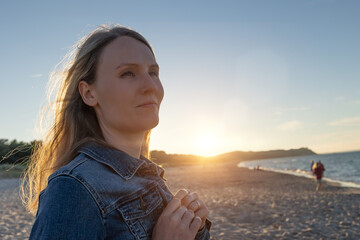 Blonde Frau bei Sonnenuntergang am Strand