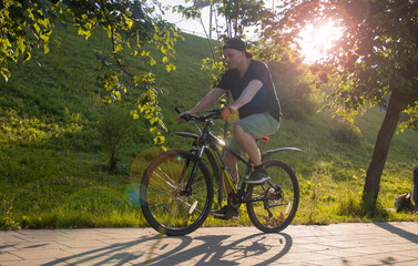 Fototapeta na wymiar A guy rides a bike in the park. Young fit man during a bike ride on a sunny day. Blurred focus