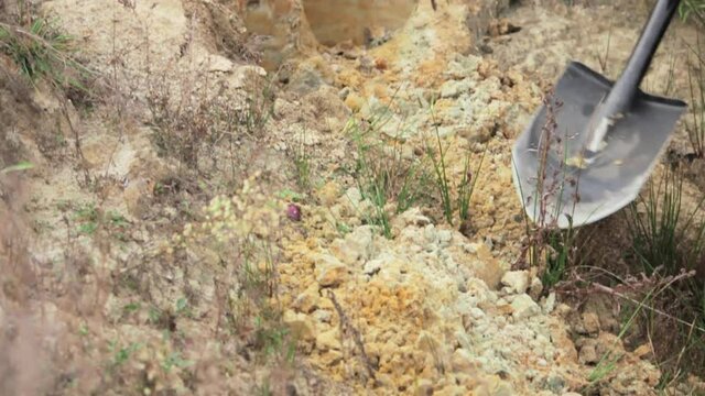 Man digging clay soil with shovel on sunny day close up.