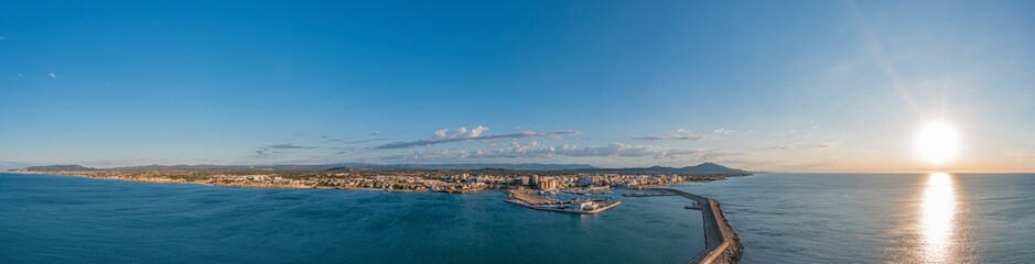 Fototapeta na wymiar Drone panorama of the Spanish town of Vinaros with the large breakwater at the entrance to the port during sunrise