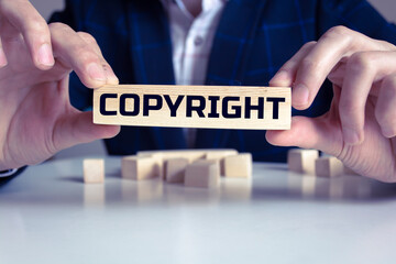 Businessman showing Copyright word in wooden block. Business concept