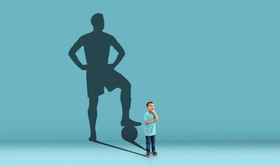 Childhood and dream about big and famous future. Conceptual image with boy and shadow of fit male football player on blue background. Dreams, imagination, education concept.