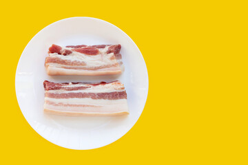 Streaky pork in white plate on yellow background.