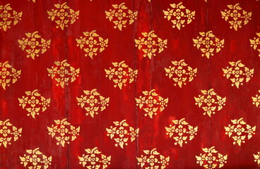 Golden color Thai native pattern on red painted wood background, favorite ancient flower pattern in temple in Thailand.