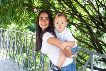 Fototapeta premium young pretty brunette mother with little cute boy walking in park happy smiling, lifestyle people concept