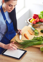 Young woman cutting vegetables in kitchen at home