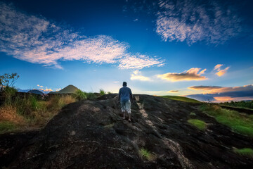 An adult standing on a mountain against beautiful sunset background. 