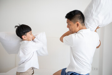 Obraz premium Happy Asian family with son at home on the bedroom playing pillow with father and laughing