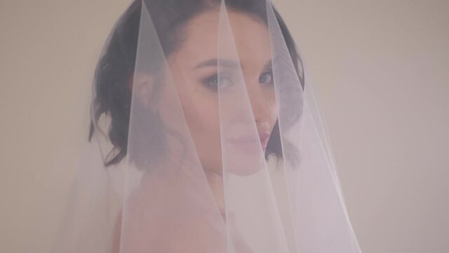 Close-up portrait of a bride in a dress with a veil that covers her head.