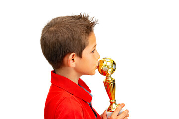 Boy soccer player in red polo shirt kisses his gold winner cup. Close-up in profile of a child with...