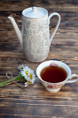 Cup of chamomile tea and chamomile flowers on wooden background. Close-up.