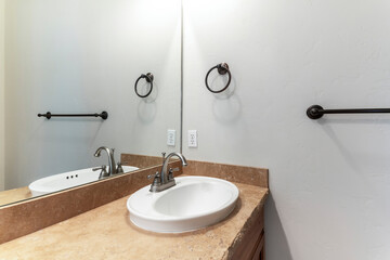 Sink with granite countertop and a mirror inside the interior of a bathroom