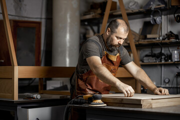 Brutal master carpenter prepares wooden blanks for work in workshop