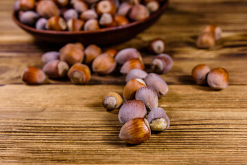 Plate with pile of hazelnuts on a wooden table