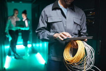 Cropped shot of network engineer using digital tablet in server room during maintenance work in...