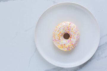 Donuts on a white plate on white marble surface. Photo flat lay, top view.