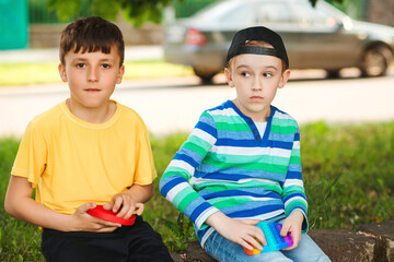 Cute boys playing with trendy pop it toy. Friends on a walk with silicon bubble toys.