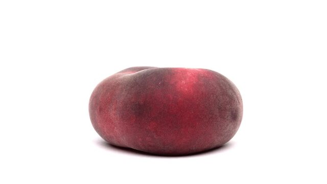 Closeup of one flat peach rotating on the turntable. Isolated on white background.
