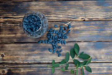 Honeysuckle in a glass glass on a wooden background is the first spring useful berries with...