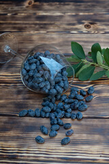 Honeysuckle in a glass glass on a wooden background is the first spring useful berries with...