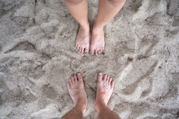 Barefoot couple standing together on the beach in vacation