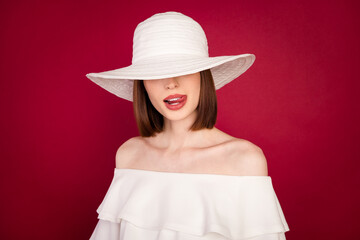 Photo portrait pretty brunette wearing hat covering eyes licking lips isolated red color background
