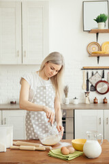 Young beautiful woman kneads dough for baking cookies