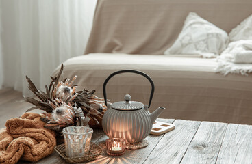 Teapot with tea and candles on the wooden table.