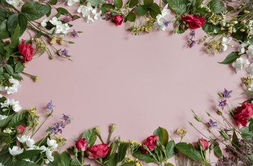 Floral frame of roses and other flowers on a pink background.
