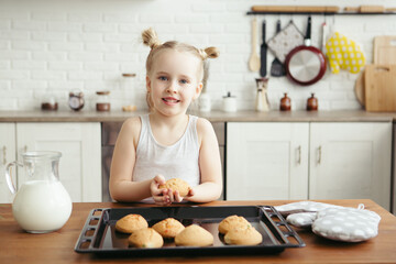 Cute little girl eating freshly baked cookies in the kitchen