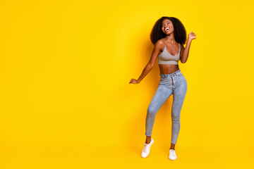 Photo of crazy excited cute lady festive mood dance wear grey cropped top jeans footwear isolated yellow color background
