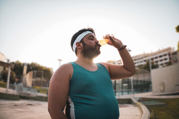 
a fat boy drinking a drink to recover.