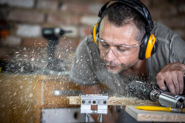 A male joiner blows wood off a board.