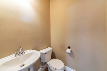 Powder room with tan colored walls , toilet bowl and sink