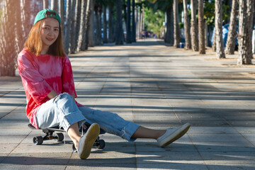 woman teennager wearing sportwear and shoes playing,sitting on surf skate on the road oudoor in the morning. Relax and enjoy extreme surfskate on summer holiday at the beach.