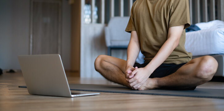 Man workout at home by study and learn do yoga online from laptop computer in the morning. exercise in door living room.