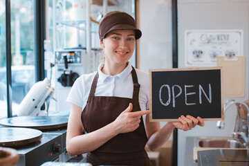 young beautiful woman in an apron a cafe worker holds a sign open against
