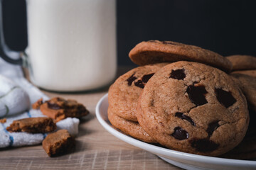 cookie chocolate chip breakfast snack bakery dessert with milk. sweet breakfast in the mornong ,unhealthy food on wooden table and dark black background.